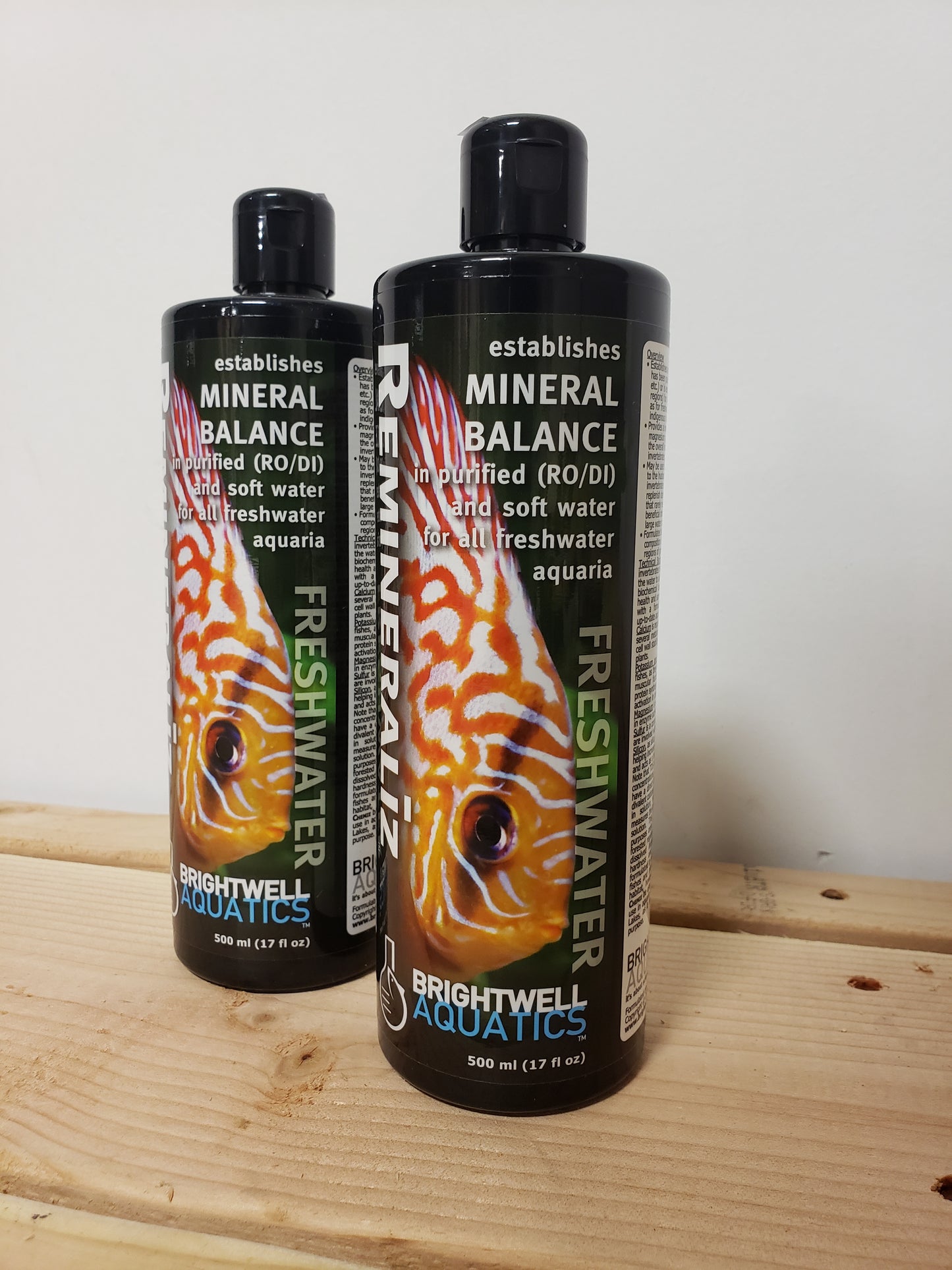 Two bottles of Brightwell Aquatics aquarium water treatment products placed on a wooden surface.