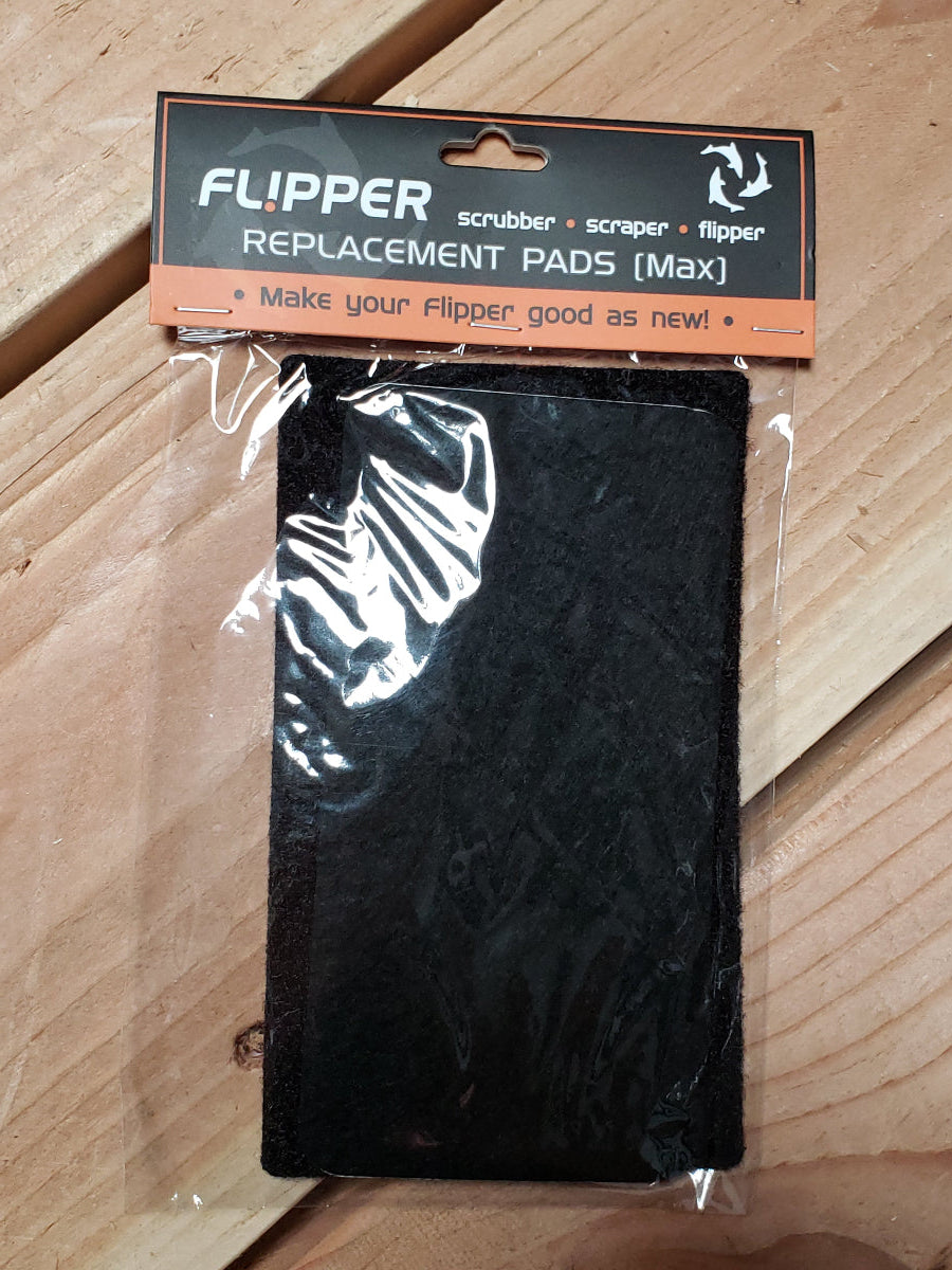 A pair of black Flipper MAX replacement pads for traction pads, packaged in a clear plastic bag with a label that includes the product name and brand.